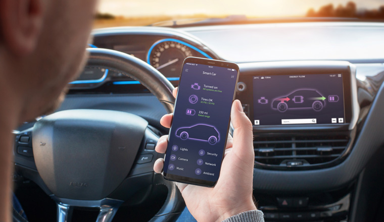 Smart Car app with engine, tyres and battery status information concept. Driver holds a mobile phone. Steering wheel and board display in the background