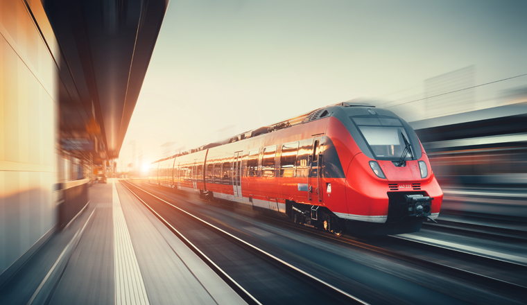 Beautiful railway station with modern high speed red commuter train with motion blur effect at colorful sunset in Nuremberg, Germany. Railroad with vintage toning