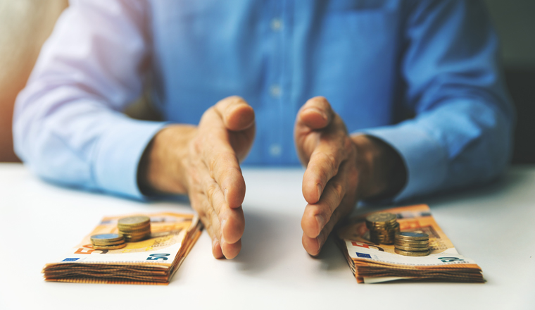 finance management and budget planning concept - businessman splitting the money on the table