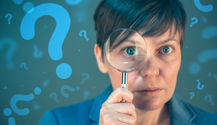 Businesswoman with question marks looking for answers, questioning and wondering about uncertain future in corporate business