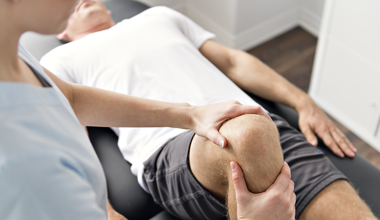 A Patient at the physiotherapy doing physical exercises with his therapist