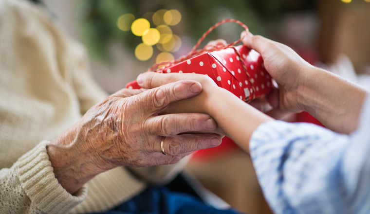 Close-up of hands of senior and young woman holding a present at Christmas time.
