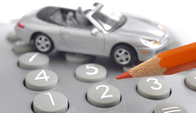 Modellauto, Taschenrechner und Rotstift als Symbol für steigende Autokosten