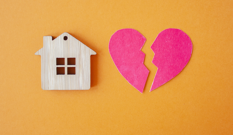 Divorce, division of property, poverty and no money concept. Wooden house with broken heart on bright orange  background. Mortgage, rent, realtor