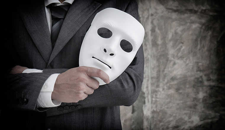 Businessman holding white mask in his hand dishonest cheating agreement.Faking and betray business partnership concept