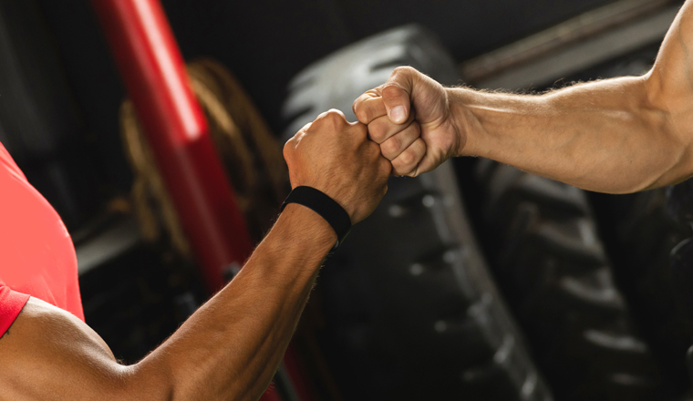 Respect in sport. Two muscular men are making fist bump gesture during workout in the gym.