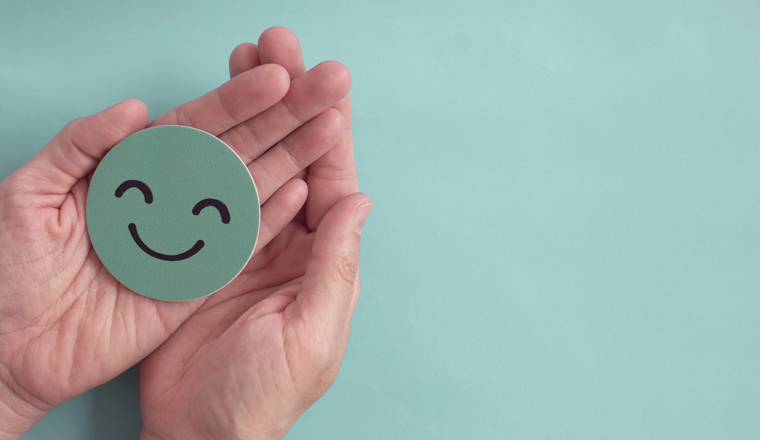 Hands holding green happy smile face paper cut, good feedback rating and positive customer review, experience, satisfaction survey ,mental health assessment, child wellness,world mental health day concept