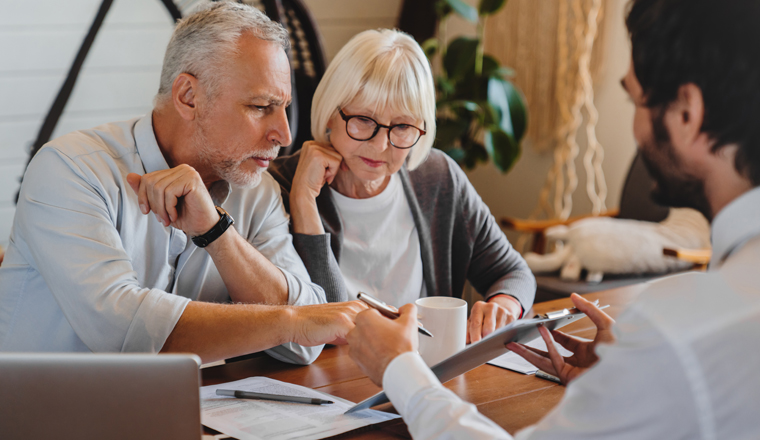 Financial advisor explaining paperwork to elderly retired couple front of desk