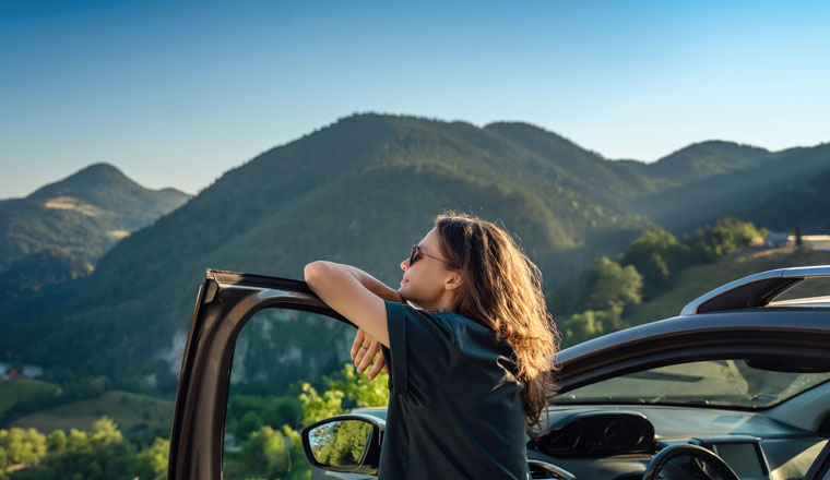 Young beautiful woman traveling by car in the mountains, summer vacation and adventure