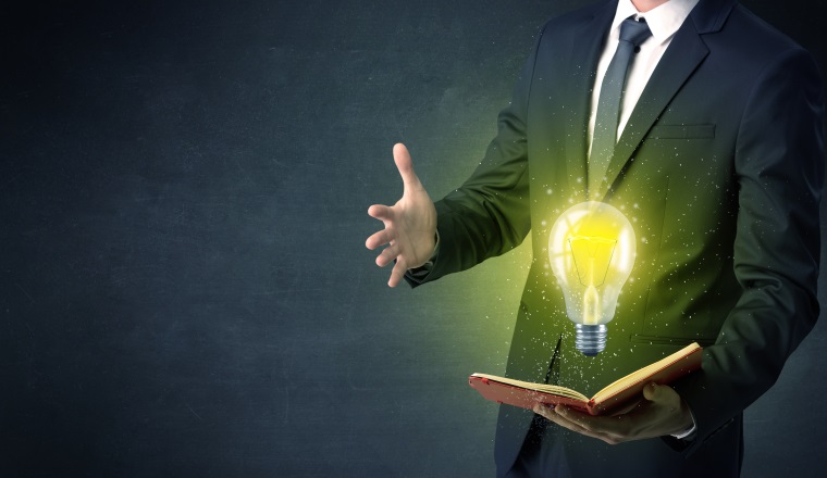 Businessman holding book with bulb.