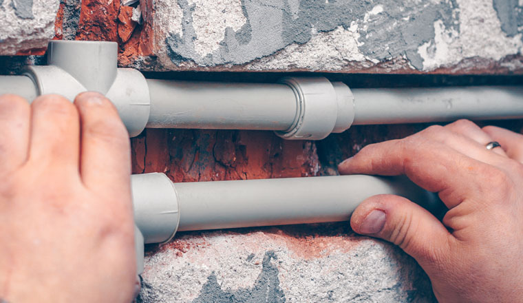 The worker carries out plumbing works in the house, mounts water pipes from polypropylene